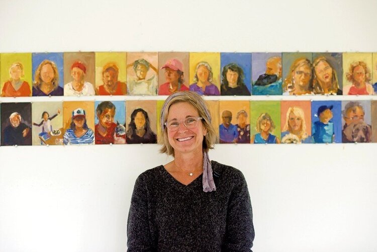 photo of Rebecca Kinkead standing in front of some of her Downtown Middlebury portraits