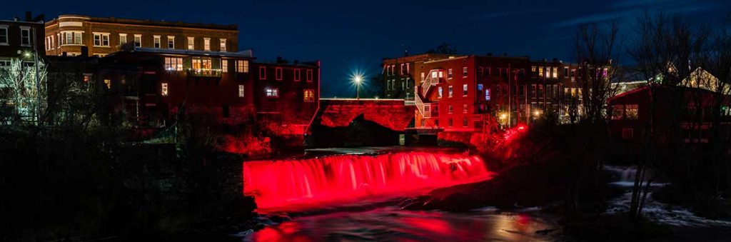 The falls in downtown Middlebury VT lit with red lights
